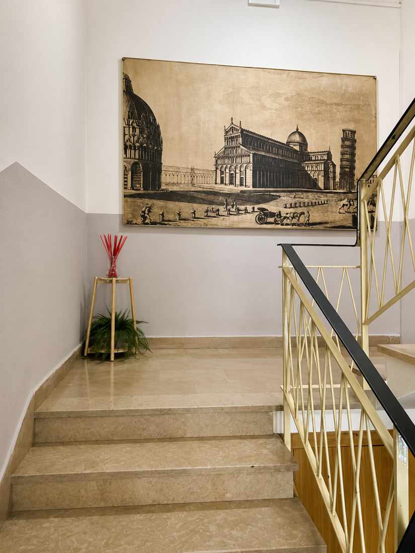 Scala in marmo con ringhiera dorata e una stampa di Piazza dei Miracoli