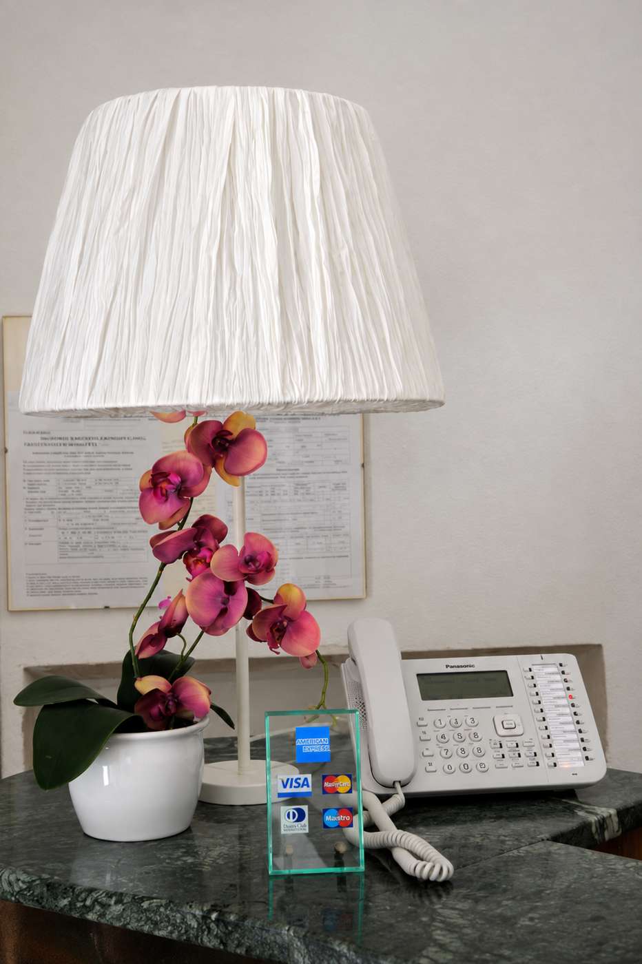 Lampada, orchidea e telefono sul banco della reception dell'Hotel Cecile