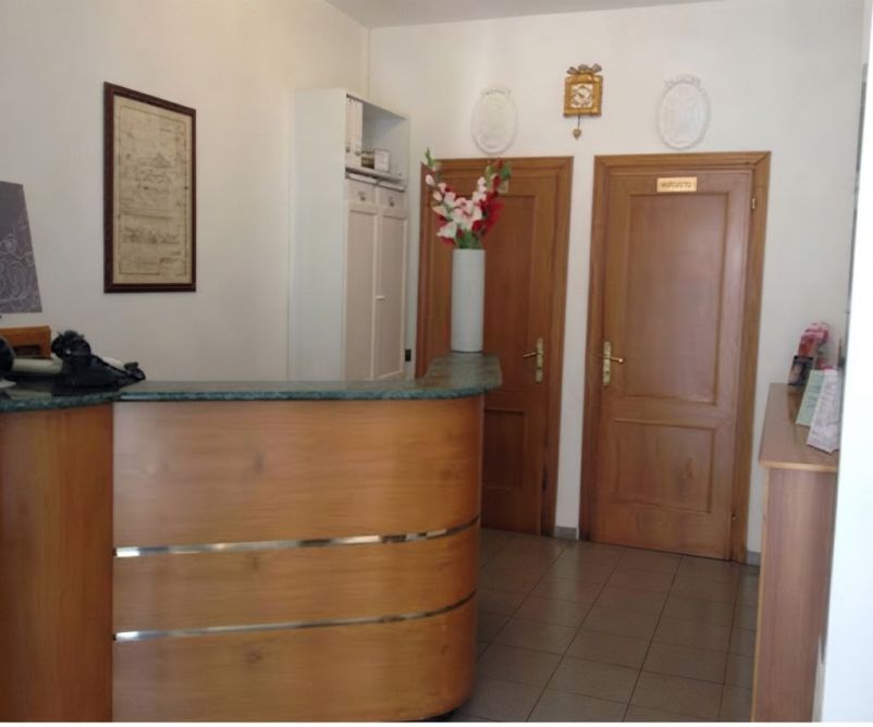 Il banco della reception e le porte sul fondo all'Hotel Cecile